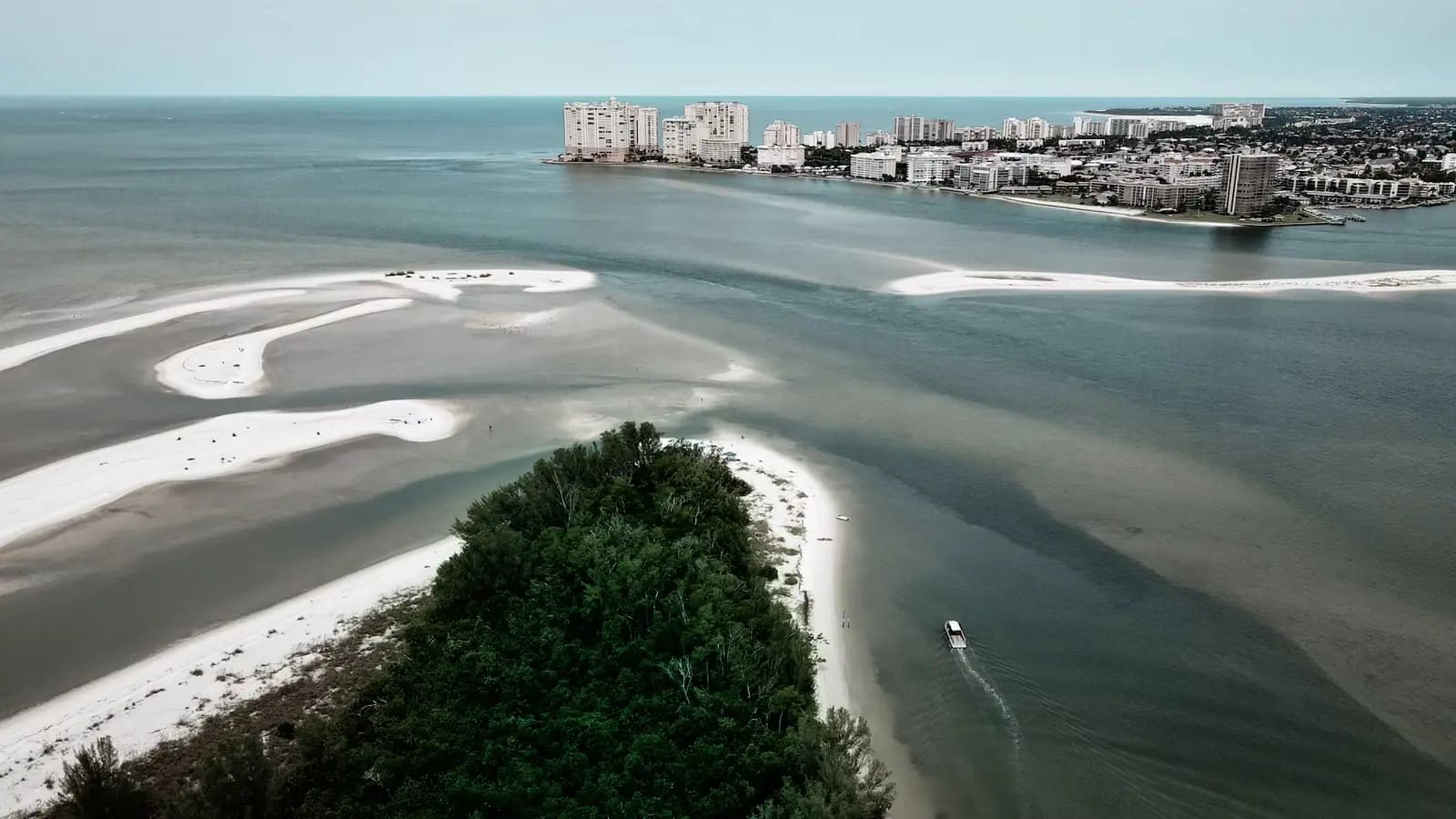 Aerial view of Marco Island's beach with mid-rise resort buildings along the shoreline above pale green Gulf water