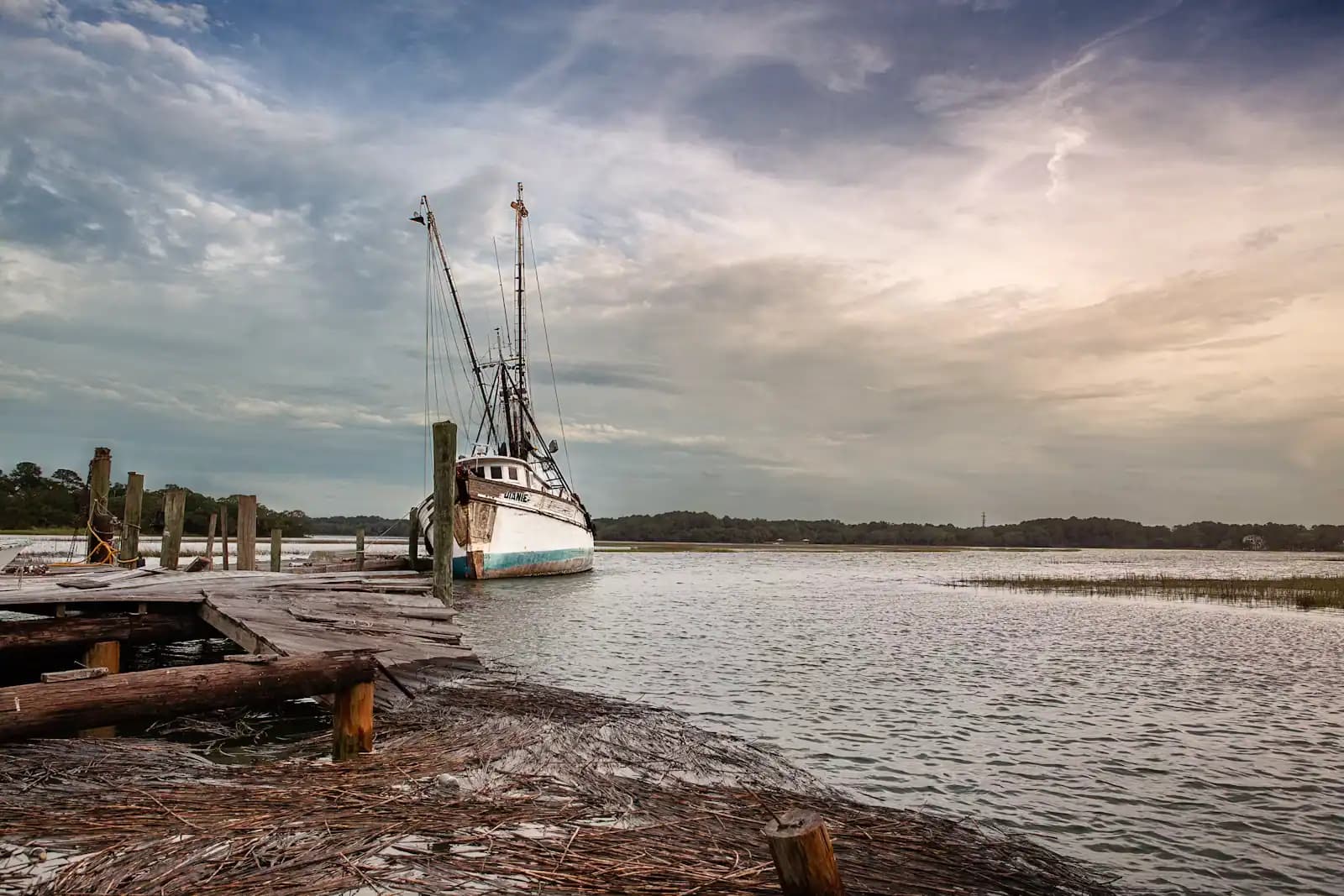 A charter boat tied alongside a floating dock on a grey, still morning
