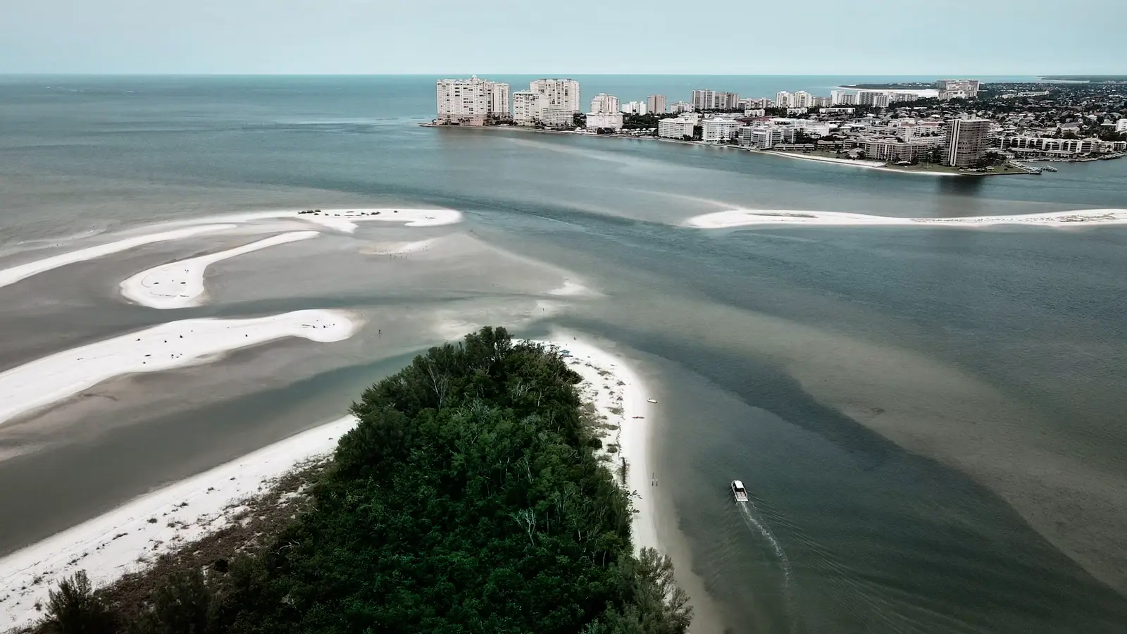 Aerial view of Marco Island's beach with mid-rise resort buildings along the shoreline above pale green Gulf water