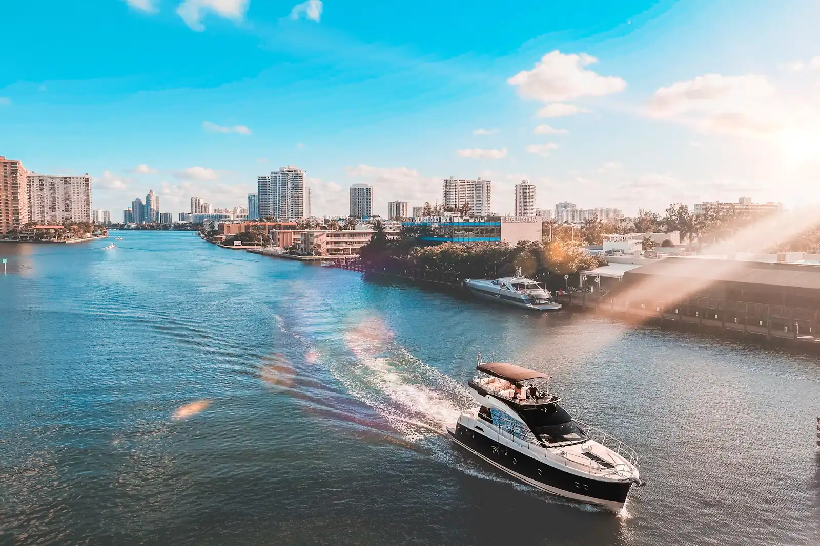 A motor yacht heading down a waterway lined with residential high-rise towers