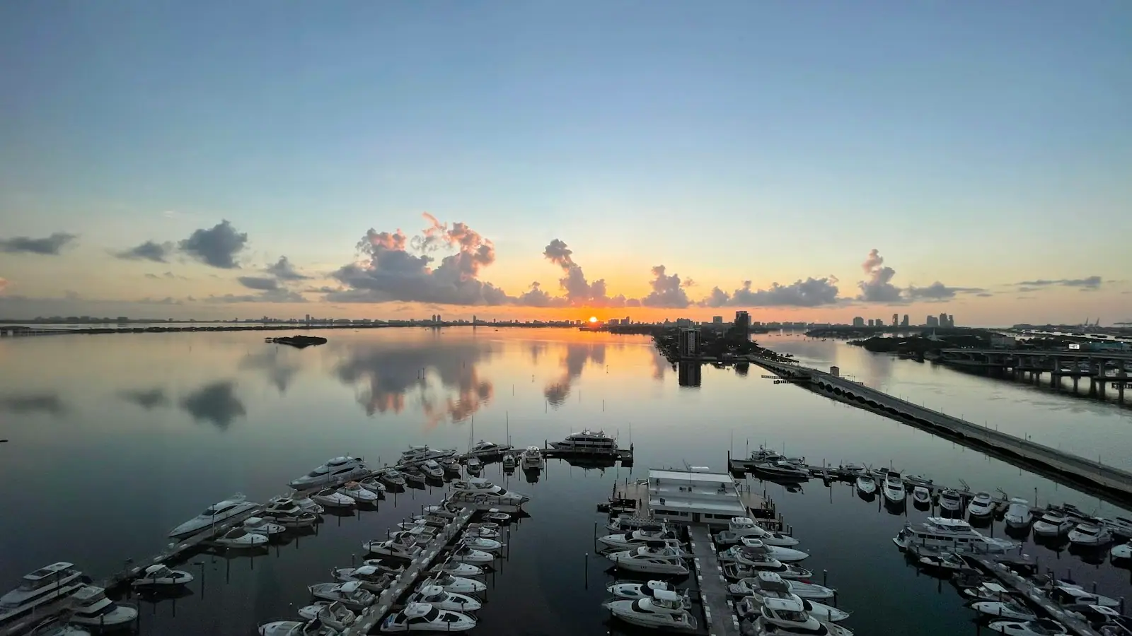 Rows of boats moored in a marina basin on flat water at first light