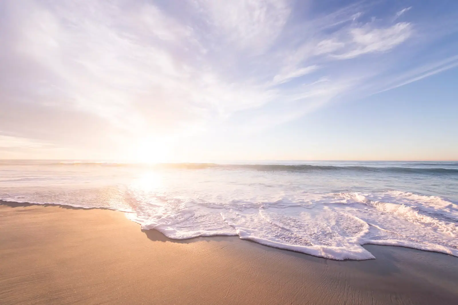 Low sun across a thin sheet of water lying on an exposed sand flat at low tide